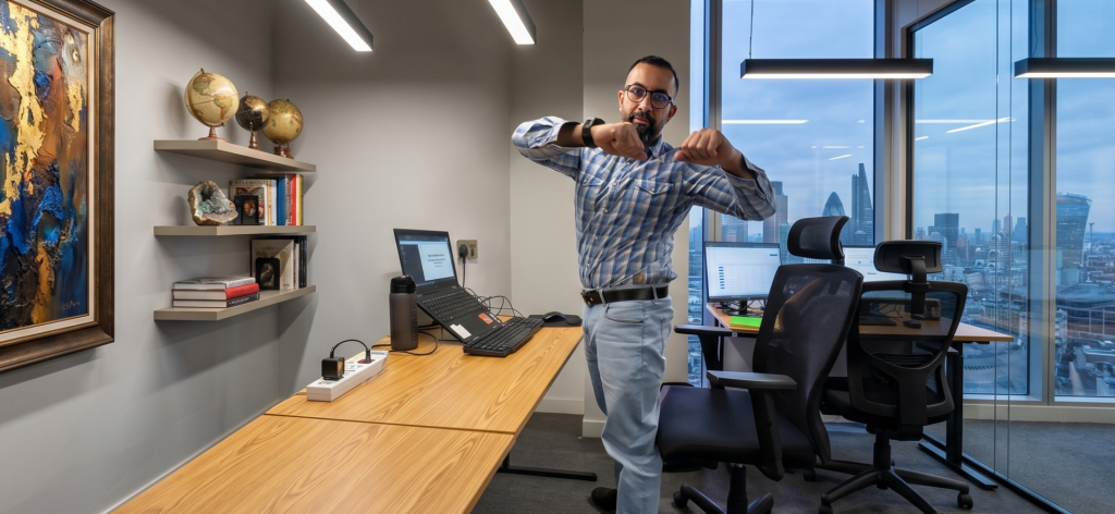 A high-performing executive doing a 2-minute standing desk reset in a corner office to beat the 3 PM energy crash and improve posture.